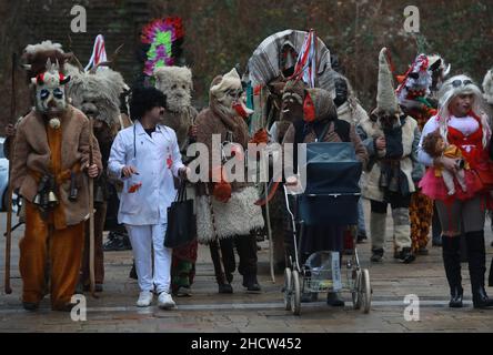 Mummers in traditionellen Kostümen tourten am ersten Tag des Jahres 2022 durch die Straßen von Godech. Menschen mit einer Maske namens Kukeri tanzen Stockfoto