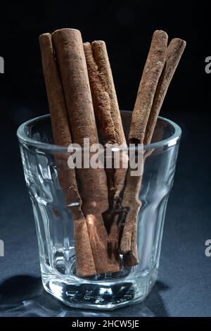 Helsinki / Finnland - 1. Januar 2022: Nahaufnahme von Zimtstangen auf einem kleinen Glas vor dunklem Hintergrund. Stockfoto