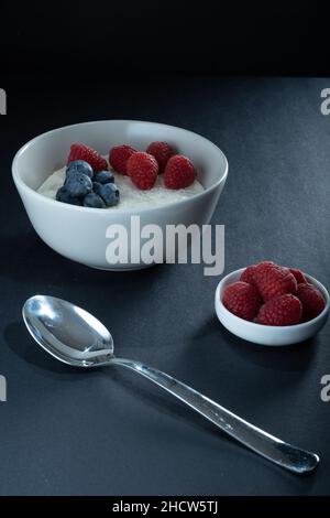 Helsinki / Finnland - 1. JANUAR 2022: Traditionelle finnische Speisen: Eine Schüssel mit Grießbrei mit Blaubeeren und Himbeeren. Stockfoto