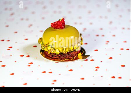 Selbstgebackene Avocado-Torte mit Sahnehäubchen, süßer Creme und Nüssen auf weißem Hintergrund mit Herzen, Nahaufnahme Stockfoto