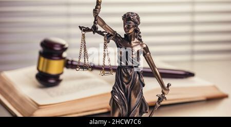 Justizstatue mit einem Gavel auf einem offenen Gesetzbuch Stockfoto