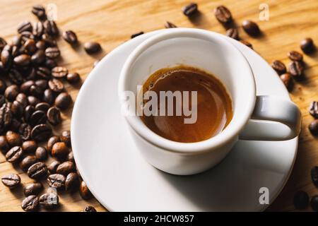 Espresso-Tasse mit gerösteten Bohnen auf Holztischhintergrund Stockfoto