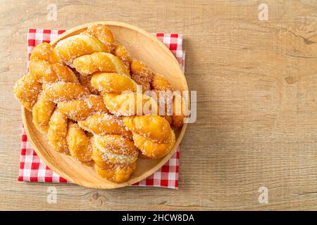 Zuckerdonut in Spiralform auf Holzplatte Stockfoto