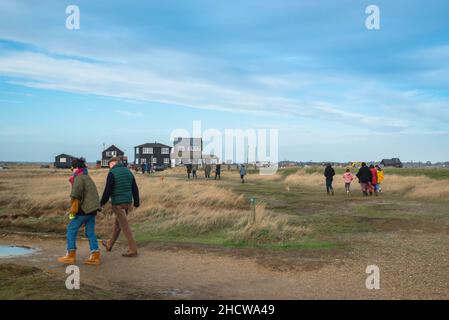 Winter Walking UK, Blick außerhalb der Saison von Menschen, die an Sumpfgebieten an der Küste von Suffolk in Walberswick, England, vorbeilaufen Stockfoto