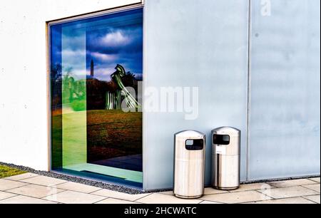 Metallabfallbehälter vor einem trostlosen, leeren Gebäude Stockfoto