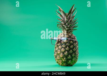 Interpretation der Ananasfrucht im menschlichen Bild wie in der Augenheilkunde mit einer Brille auf grünem Hintergrund. Speicherplatz kopieren Stockfoto