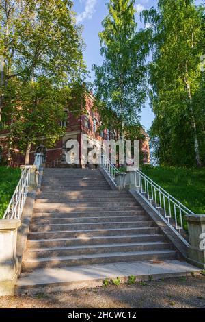 An einem sonnigen Sommertag führt eine Treppe zu einem alten Gebäude im Hatanpää Arboretum in Tampere, Finnland. Stockfoto