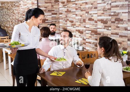 Kellnerin nimmt Tischbestellung in der Taverne an Stockfoto