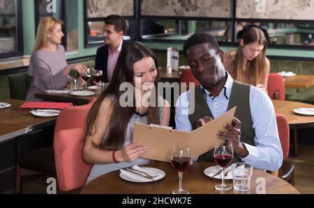 Romantisches Paar, das Gerichte von der Speisekarte des Restaurants auswählt Stockfoto