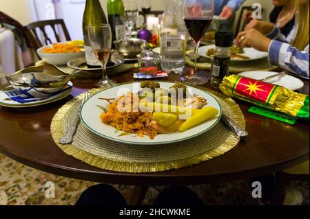 Ein Teller Weihnachtsessen auf einem Esstisch mit unfokussieren Händen von Menschen, die im Hintergrund essen Stockfoto