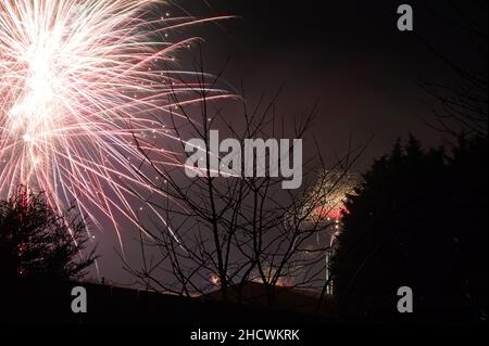 Blick aus einem Garten mit farbenfrohen Feuerwerken am Nachthimmel, die das neue Jahr 2022 feiern Stockfoto