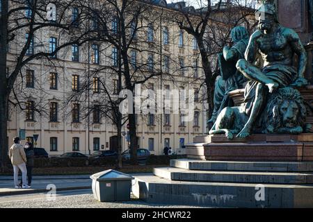 Ein Paar mit Covid-Masken wartet am Max-Denkmal in München, einem großen Denkmal zu Ehren des bayerischen Königs Maximilian II. Stockfoto