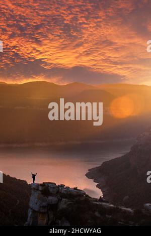 Silhouette einer abenteuerlichen Person, die eine beeindruckende Landschaft bei Sonnenuntergang betrachtet. Morro de l'Abella, Osona, Barcelona, Katalonien. Eine der meisten s Stockfoto