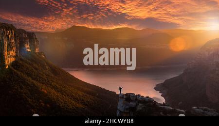 Silhouette einer abenteuerlichen Person, die eine beeindruckende Landschaft bei Sonnenuntergang betrachtet. Morro de l'Abella, Osona, Barcelona, Katalonien. Eine der meisten s Stockfoto