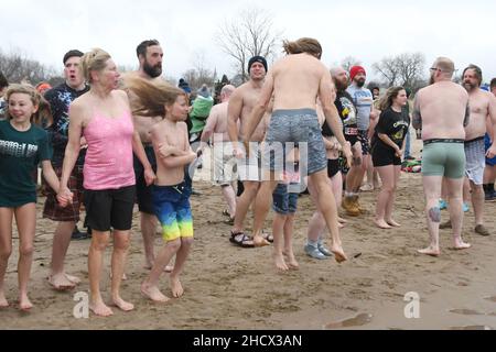 Racine, Wisconsin, USA. 1st Januar 2022. Ein Schwimmer springt zum Aufwärmen, bevor der jährliche Neujahrseisbär Splash and Dash am Samstag, den 1. Januar 2022, in Racine, Wisconsin, in den Lake Michigan eintaucht. Der Erlös aus der Veranstaltung geht an lokale Wohltätigkeitsorganisationen, darunter eine Lebensmittelbank und ein Obdachlosenheim. Die Wassertemperatur lag bei 40 Grad, und der Windchill-Index bei 19 Grad. Der erste Schneesturm der Saison - mit 4 bis 8 Zoll vorhergesagt - begann kurz nach dem Ereignis. (Bild: © Mark Hertzberg/ZUMA Press Wire) Stockfoto