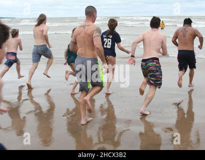 Racine, Wisconsin, USA. 1st Januar 2022. Schwimmer laufen am jährlichen Neujahrstag am Samstag, den 1. Januar 2022, in Racine, Wisconsin, in den See, wo der Eisbär Splash und Dash eintauchen. Der Erlös aus der Veranstaltung geht an lokale Wohltätigkeitsorganisationen, darunter eine Lebensmittelbank und ein Obdachlosenheim. Die Wassertemperatur lag bei 40 Grad, und der Windchill-Index bei 19 Grad. Der erste Schneesturm der Saison - mit 4 bis 8 Zoll vorhergesagt - begann kurz nach dem Ereignis. (Bild: © Mark Hertzberg/ZUMA Press Wire) Stockfoto