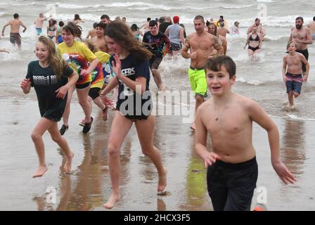 Racine, Wisconsin, USA. 1st Januar 2022. Schwimmer eilen nach der Teilnahme am jährlichen Neujahrstag, am Samstag, den 1. Januar 2022, stürzen sich die Eisbären Splash und Dash in den Lake Michigan in Racine, Wisconsin. Der Erlös aus der Veranstaltung geht an lokale Wohltätigkeitsorganisationen, darunter eine Lebensmittelbank und ein Obdachlosenheim. Die Wassertemperatur lag bei 40 Grad, und der Windchill-Index bei 19 Grad. Der erste Schneesturm der Saison - mit 4 bis 8 Zoll vorhergesagt - begann kurz nach dem Ereignis. (Bild: © Mark Hertzberg/ZUMA Press Wire) Stockfoto