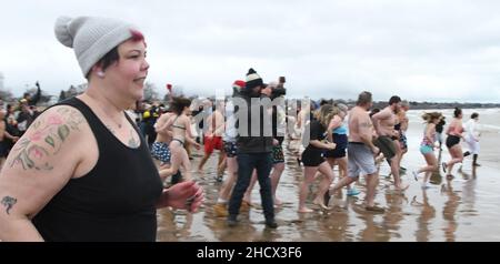 Racine, Wisconsin, USA. 1st Januar 2022. Schwimmer laufen am jährlichen Neujahrstag am Samstag, den 1. Januar 2022, in Racine, Wisconsin, in den See, wo der Eisbär Splash und Dash eintauchen. Der Erlös aus der Veranstaltung geht an lokale Wohltätigkeitsorganisationen, darunter eine Lebensmittelbank und ein Obdachlosenheim. Die Wassertemperatur lag bei 40 Grad, und der Windchill-Index bei 19 Grad. Der erste Schneesturm der Saison - mit 4 bis 8 Zoll vorhergesagt - begann kurz nach dem Ereignis. (Bild: © Mark Hertzberg/ZUMA Press Wire) Stockfoto