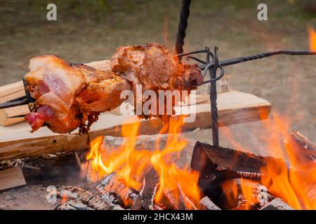 Prozess des Kochens großer Fleischstücke auf Spieß über offenem Feuer Stockfoto