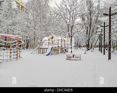 Ein leerer und schneebedeckter Kinderspielplatz am frühen Dezembermorgen Stockfoto