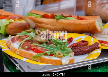 Sandwich mit Rucola, Schinken, Käse, Jalapeno, getrockneten Tomaten, Salami - Nahaufnahme Stockfoto