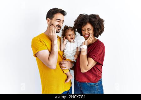 Interracial junge Familie von schwarzer Mutter und hispanischen Vater mit Tochter berühren Mund mit der Hand mit schmerzhaften Ausdruck wegen Zahnschmerzen oder de Stockfoto