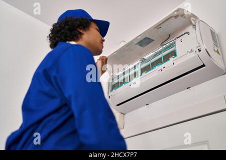 Junger hispanischer Techniker, der die Klimaanlage zu Hause repariert Stockfoto