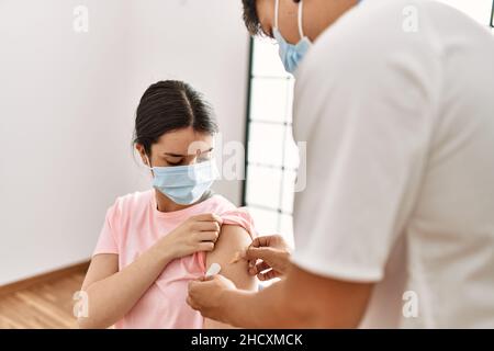 Junge Krankenschwester Mann legte Band Hilfe auf Frau Arm in der Klinik. Stockfoto