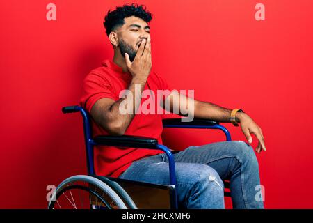 Arabischer Mann mit Bart auf dem Rollstuhl sitzend gelangweilt gähnend müde den Mund mit der Hand bedeckend. Unruhig und müde. Stockfoto