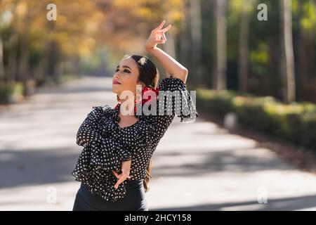 Frau in einem Flamenco-Kleid und Nelken auf ihrem Kopf tanzen im Freien Stockfoto