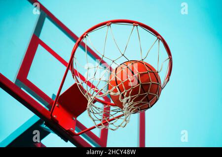 Ein Basketball im Netz. Die Fliege ist im Ring. Ein Sportspiel. Konzeptionell: Sieg, Erfolg, Zielerreichungen, Sport. Erfolgreicher Ballwurf. Stockfoto