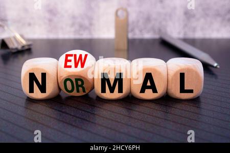 Handliches Flippen von Holzklotzwürfeln für neue normale Aufschrift. Die Welt verändert sich, um es in neue Normalität einschließlich Geschäft, Wirtschaft, Umwelt auszugleichen Stockfoto