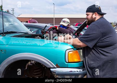 Zwei Männer arbeiten daran, Teile von einem blauen Ford Ranger Pickup-Truck auf dem LKQ Pick Your Part Auto Bergungshof in Fort Wayne, Indiana, USA zu entfernen. Stockfoto