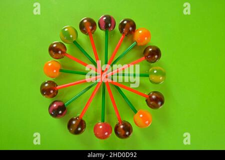 Verschiedene bunte Lutscher auf pastellfarbenem Hintergrund. Helle, saftige Lutscher auf grünem Hintergrund. Lutscher in Form einer Blume. Fruchtbonbons. Stockfoto