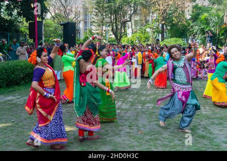 Kalkutta, Indien - 21.. März 2019: Tanzende Mädchen, bekleidet mit farbenfrohem Sari (traditionelles indisches Kleid) und Palashblumen (Butea monosperma). Stockfoto