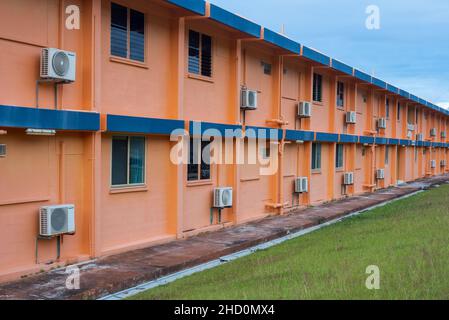 Klimaanlagen, die an der Außenseite eines orangefarbenen Apartmentblocks in Poon Saan montiert sind, einer Siedlung über Flying Fish Cove auf Christmas Island. Stockfoto