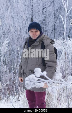 Ein Mann in Winterkleidung. Es gibt eine schneebedeckte Landschaft ringsum. Männliches Porträt. Nahaufnahme Stockfoto