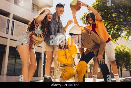 Basketball-Spaß. Gruppe junger Freunde, die fröhlich lachen, während sie Zeit zusammen in der Sonne verbringen. Gruppe von Freunden der Generation z, die Spaß mit einem BA haben Stockfoto