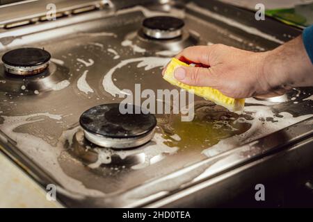 Mann wäscht Gasherd mit gelbem Schwamm, Hand Nahaufnahme Stockfoto