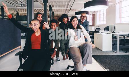 Tolle Momente festhalten. Fröhliche Geschäftsfrau, die während der Spielzeit ein Selfie mit ihren Kollegen gemacht hat. Eine Gruppe von Geschäftsleuten, die Spaß haben und feiern Stockfoto