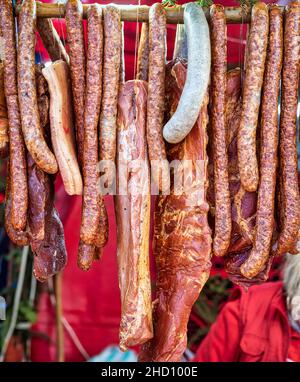 Viele geräucherte Würstchen und andere Schweinefleischprodukte hängen an einem Stock auf einem Food Festival. Stockfoto