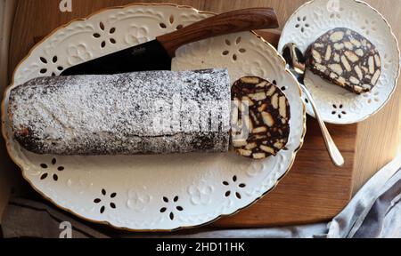 Fauler Kuchen oder Mosaikkuchen . Hausgemachter, nicht gebackener Schokoladenkuchen auf einem Holztisch Stockfoto