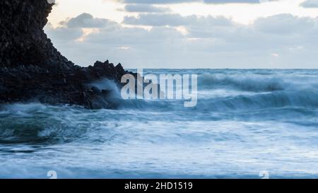 Am Piha Beach, Auckland, Neuseeland, krachen riesige Wellen gegen die Felsen. Stockfoto