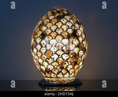 Eine schöne ovale Lampe mit Details vor weißem Hintergrund in einem dunklen Raum. Stockfoto