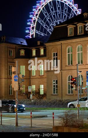 Stuttgart, 31. Dezember 2021: Riesenrad bei Nacht mit beleuchteten Gondeln hinter dem Schloss. Attraktion zu Neujahr. Wunderschönes Gebäude Stockfoto