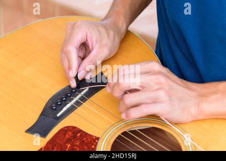 Der Musiker ersetzt die neuen Gitarrensaiten für seine Gitarre Stockfoto