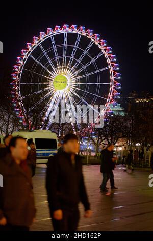 Stuttgart, 31. Dezember 2021: Riesenrad bei Nacht mit beleuchteten Gondeln. Die Attraktion zum Neujahr wird von vielen Menschen besucht. Polizeiauto kann Stockfoto