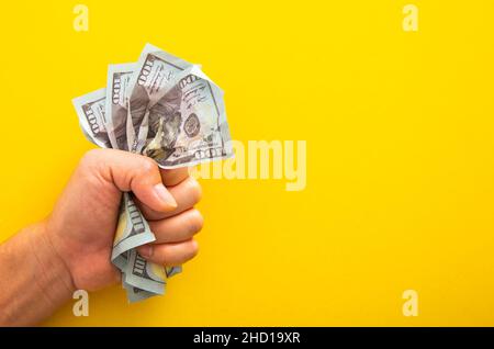 Männliche Hand drückt eine Banknote auf gelbem Hintergrund fest Stockfoto