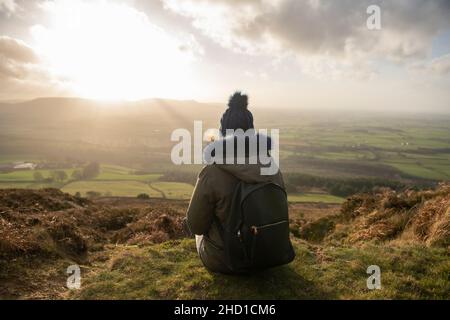 Eine Frau, die den Sonnenuntergang vom Captain Cook Monument auf dem Cleveland Way im North York Moors National Park aus beobachtet. Stockfoto