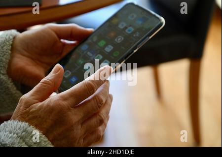 Nahaufnahme einer älteren Frau, die ein Mobiltelefon mit Apps verwendet. Stockfoto